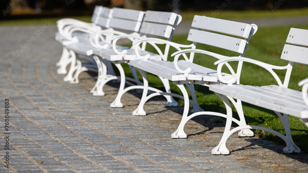 White wooden benches in a city park. A romantic photo of empty benches in sunlight