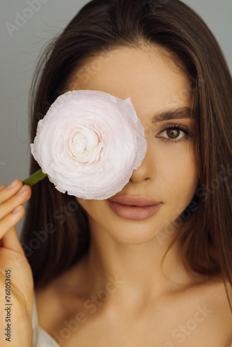 Beauty portrait of smiling young woman with pink peony in hand isolated on white background