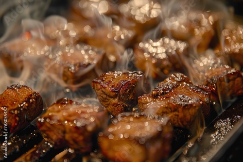 A detailed view of steak cubes sizzling as they cook on a grill, with flames and smoke rising