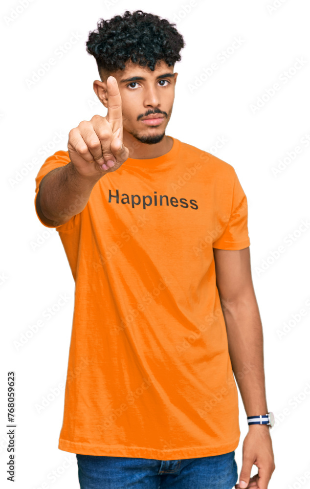 Young arab man wearing tshirt with happiness word message pointing with finger up and angry expression, showing no gesture Young arab man wearing tshirt with happiness word message pointing with finger up and angry expression, showing no gesture