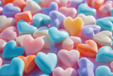 Colorful Heart Shaped Candies Arranged in a Pile with Blue, Pink and Orange Heart Shape in Center on White Surface
