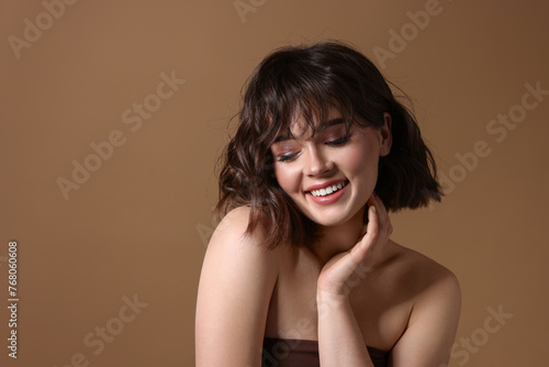 Portrait of beautiful young woman with wavy hairstyle on brown background. Space for text