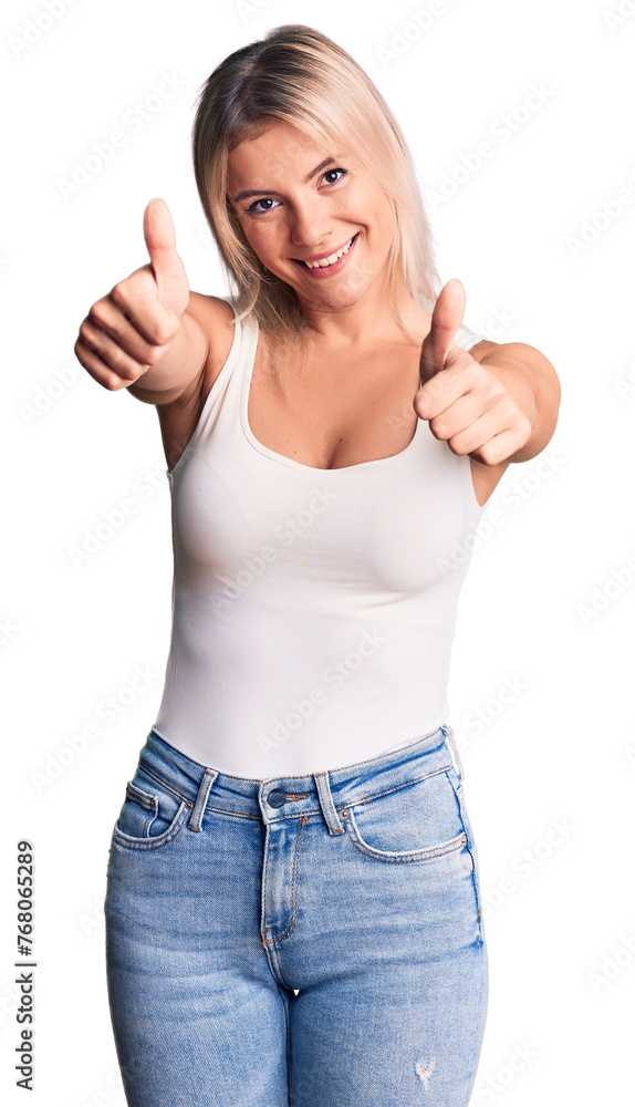 Young beautiful blonde woman wearing casual sleeveless t-shirt approving doing positive gesture with hand, thumbs up smiling and happy for success. winner gesture. Young beautiful blonde woman wearing casual sleeveless t-shirt approving doing positive gesture with hand, thumbs up smiling and happy for success. winner gesture.
