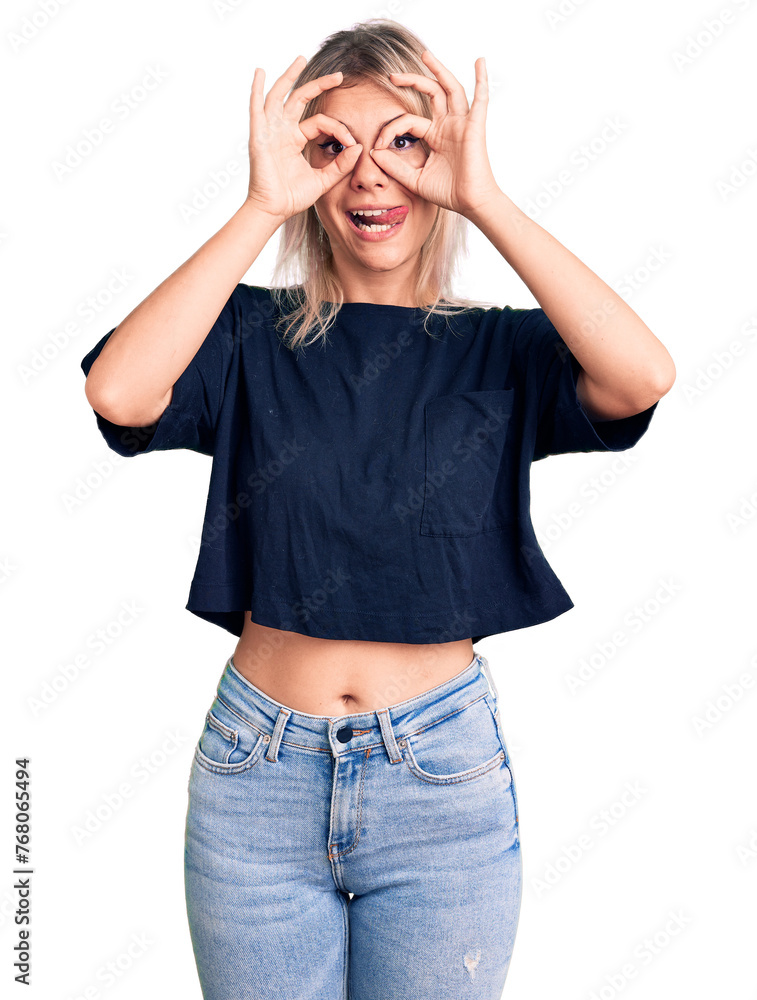 Young beautiful blonde woman wearing casual t-shirt doing ok gesture like binoculars sticking tongue out, eyes looking through fingers. crazy expression. Young beautiful blonde woman wearing casual t-shirt doing ok gesture like binoculars sticking tongue out, eyes looking through fingers. crazy expression.