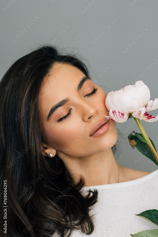 Young woman posing with peony flower over white background