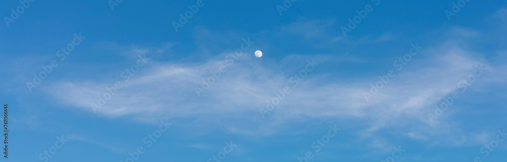 La Luna di giorno nel cielo azzurro dietro al velo di una nuvola La Luna di giorno nel cielo azzurro dietro al velo di una nuvola