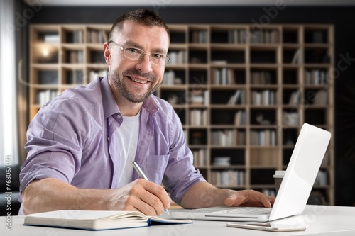 Smart male student at desk using laptop,