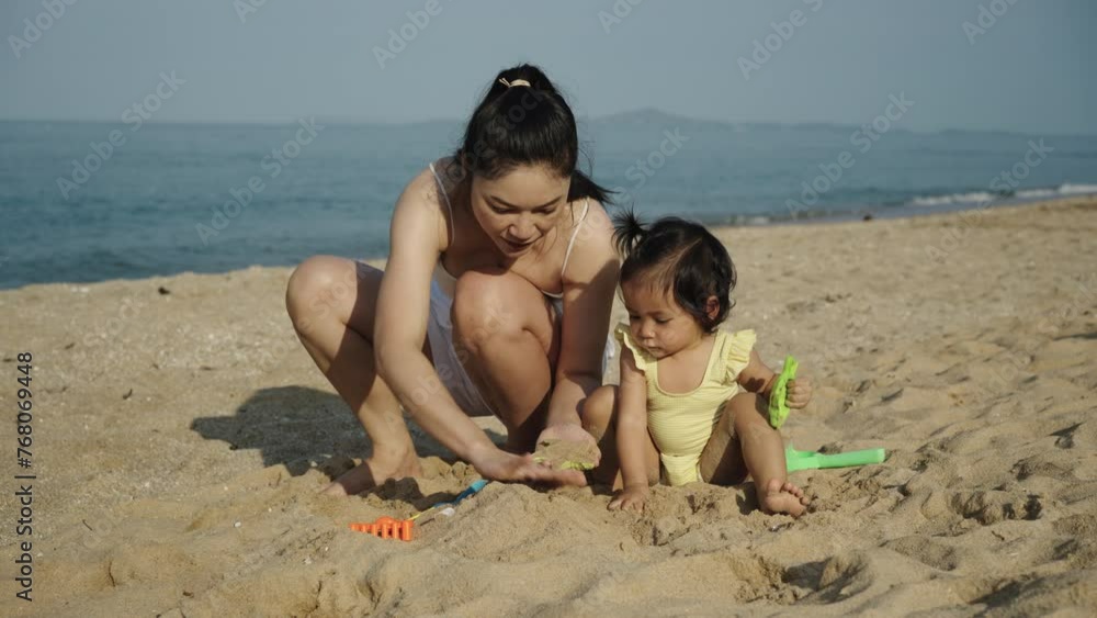 happy toddler baby girl playing sand toy with her mother on the sea beach happy toddler baby girl playing sand toy with her mother on the sea beach