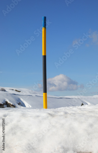 snow warning post during snowfall in the mountains in winter