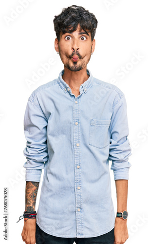 Young hispanic man wearing casual clothes making fish face with lips, crazy and comical gesture. funny expression.