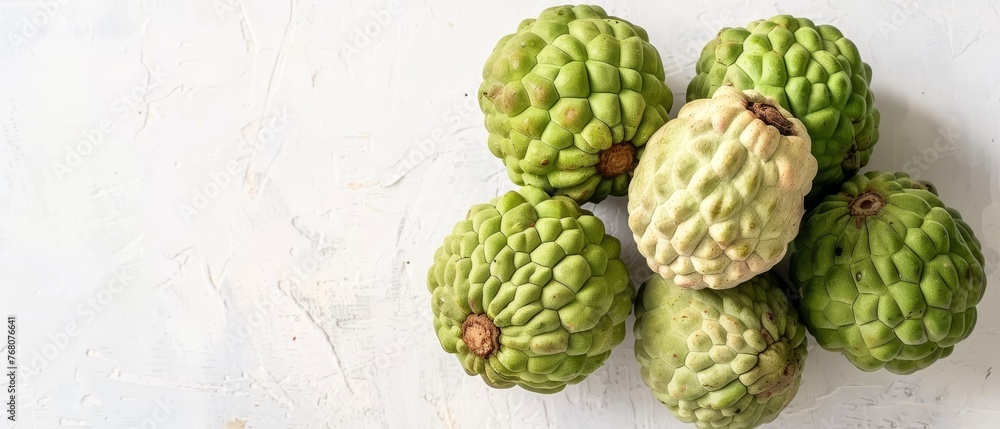 Green fruits sit on a white countertop with peeling paint on the adjacent wall Green fruits sit on a white countertop with peeling paint on the adjacent wall
