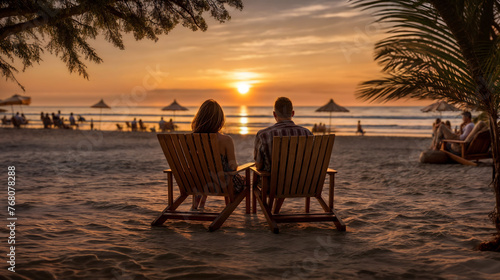 A couple sits on a beach. They are on chairs watching the sunset. Generative AI