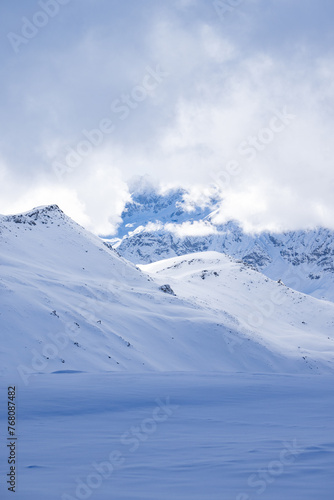 portrait of mountains covered in snow with clouds backlit 