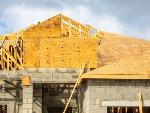 Roof under construction on top of concrete shell of a suburban single-family house in progress on a summer morning in southwest Florida photo