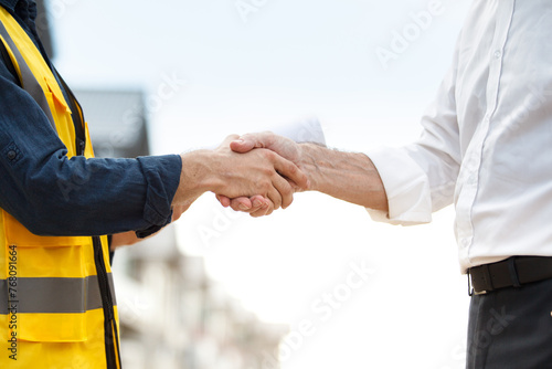 Unrecognizable foreman and businessman shaking hands together at the construction site after completely done on construction agreement. photo
