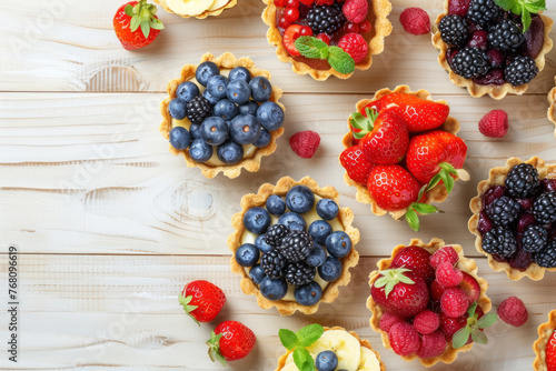 assorted fresh fruit tarts with blueberry, raspberry, and strawberry toppings