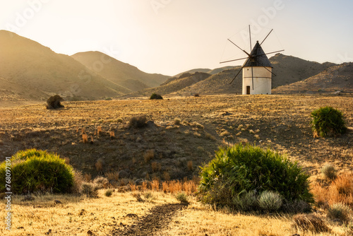 Old windmill in the field with hills and mountains in the background