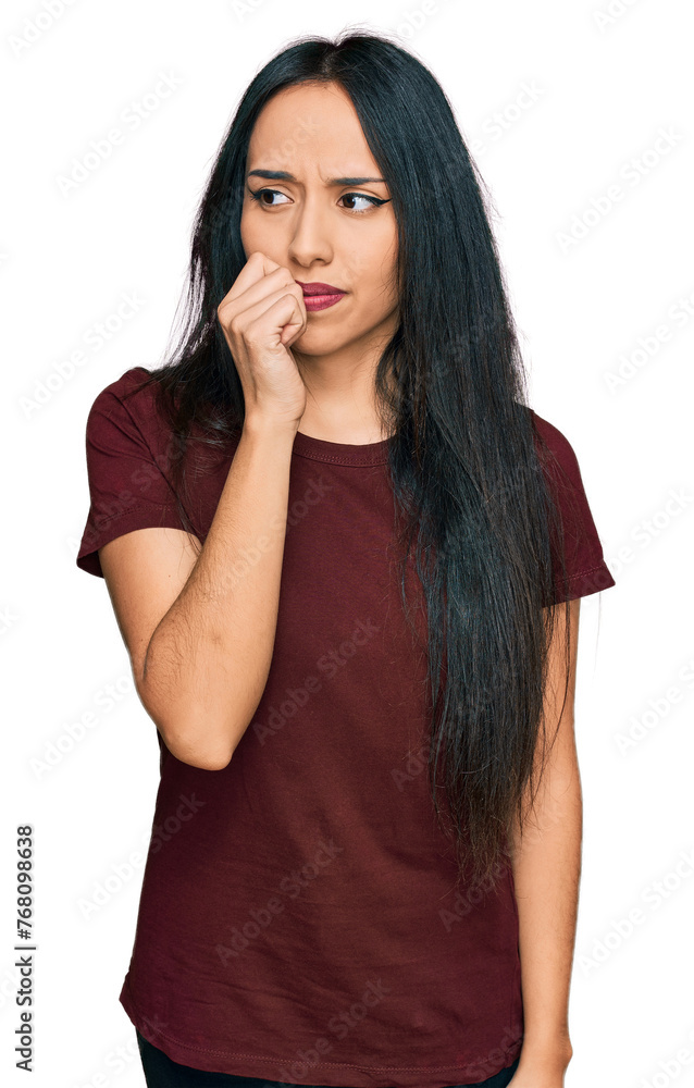 Young hispanic girl wearing casual t shirt looking stressed and nervous with hands on mouth biting nails. anxiety problem. Young hispanic girl wearing casual t shirt looking stressed and nervous with hands on mouth biting nails. anxiety problem.