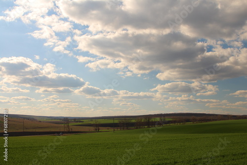 A field with a fence and blue sky with clouds