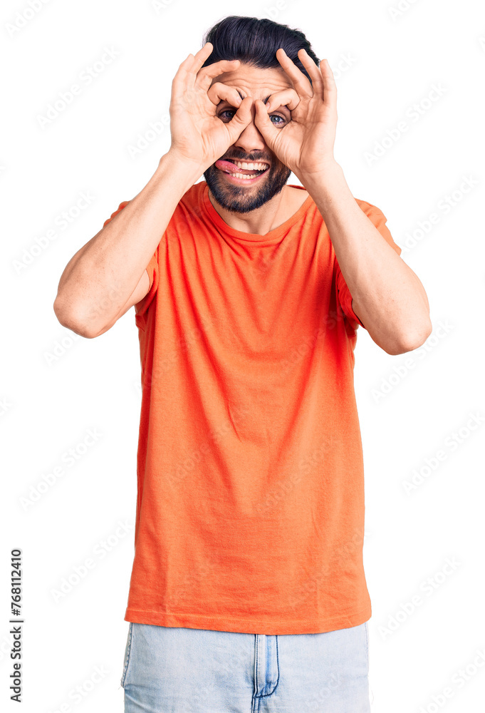 Young handsome man with beard wearing casual t-shirt doing ok gesture like binoculars sticking tongue out, eyes looking through fingers. crazy expression. Young handsome man with beard wearing casual t-shirt doing ok gesture like binoculars sticking tongue out, eyes looking through fingers. crazy expression.