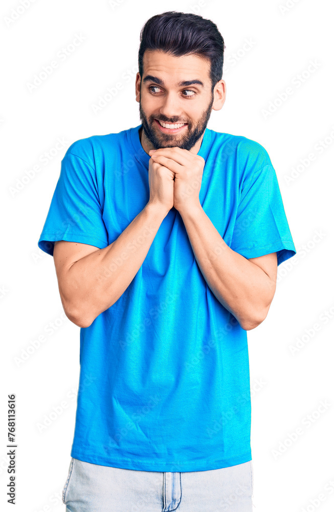 Young handsome man with beard wearing casual t-shirt laughing nervous and excited with hands on chin looking to the side Young handsome man with beard wearing casual t-shirt laughing nervous and excited with hands on chin looking to the side