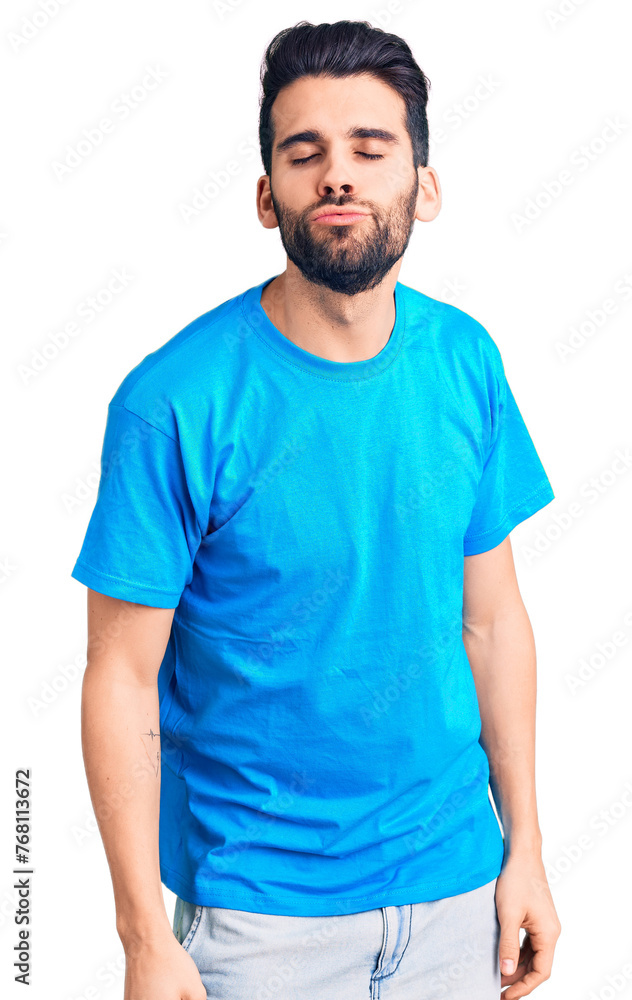 Young handsome man with beard wearing casual t-shirt looking at the camera blowing a kiss on air being lovely and sexy. love expression. Young handsome man with beard wearing casual t-shirt looking at the camera blowing a kiss on air being lovely and sexy. love expression.