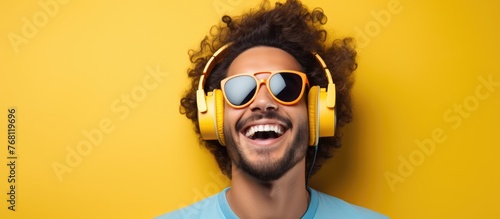 A happy young man wearing headphones and a blue shirt is listening to music or a podcast. He looks relaxed and focused, enjoying the sound in his ears. photo