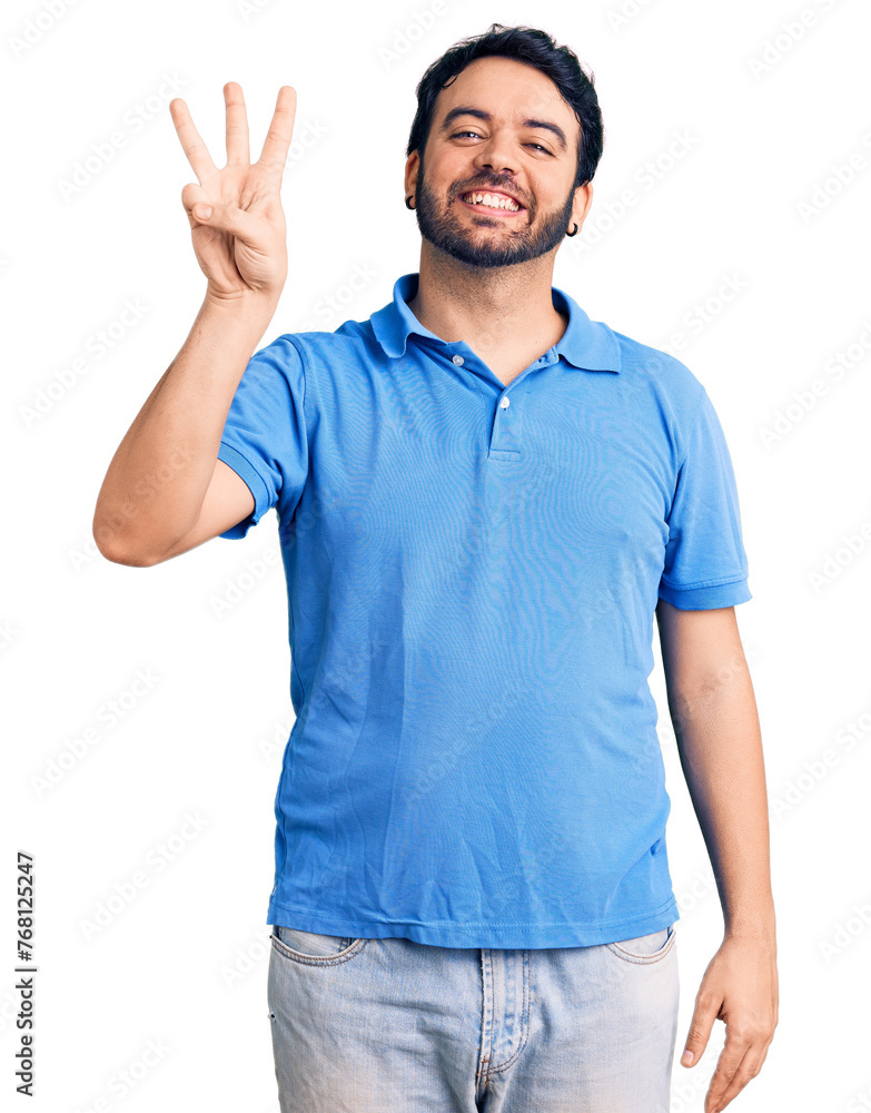 Naklejka premium Young hispanic man wearing casual clothes showing and pointing up with fingers number three while smiling confident and happy.