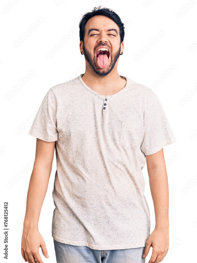 Young hispanic man wearing casual clothes sticking tongue out happy with funny expression. emotion concept. Young hispanic man wearing casual clothes sticking tongue out happy with funny expression. emotion concept.