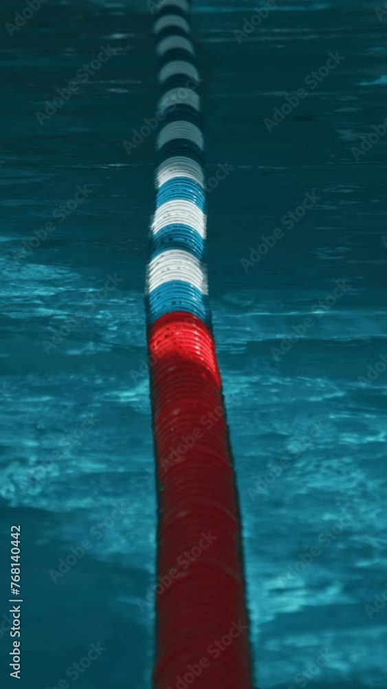 Vertical no people shot of red, blue and white plastic lane divider floating on bright turquoise surface of shimmering water in indoor swimming pool, in natural light, before openingVertical no people Vertical no people shot of red, blue and white plastic lane divider floating on bright turquoise surface of shimmering water in indoor swimming pool, in natural light, before openingVertical no people