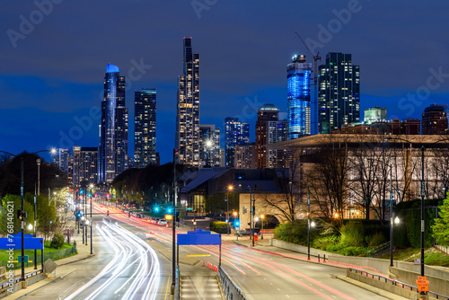 View of a urban road through a park with residential towers in background in Chicago downtown at twilight
