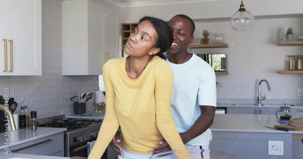 A diverse couple shares a tender moment in the kitchen, hugging A diverse couple shares a tender moment in the kitchen, hugging