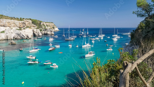 Many white yachts float on turquoise waters of Cala Macarella in Menorca Island Spain