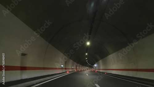 Windscreen front view POV of driving car in long underground tunnel