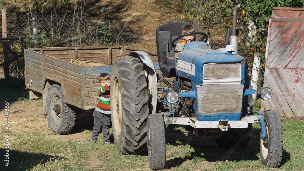 Fototapeta premium Cute little brothers try to move the tractor at the farm