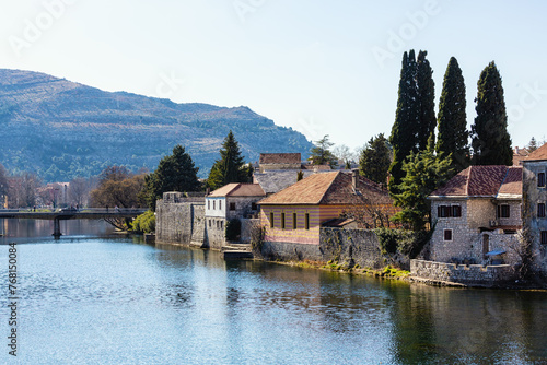 Trebinje old town by river, with stone buildings and cypress trees against a mountain backdrop, highlighting natural color harmony. Bosnia and Herzegovina