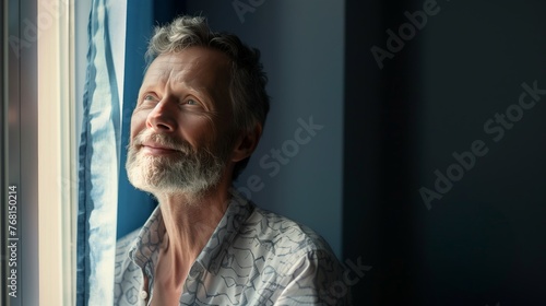 Portrait of a widower man looking up and and out a window photo