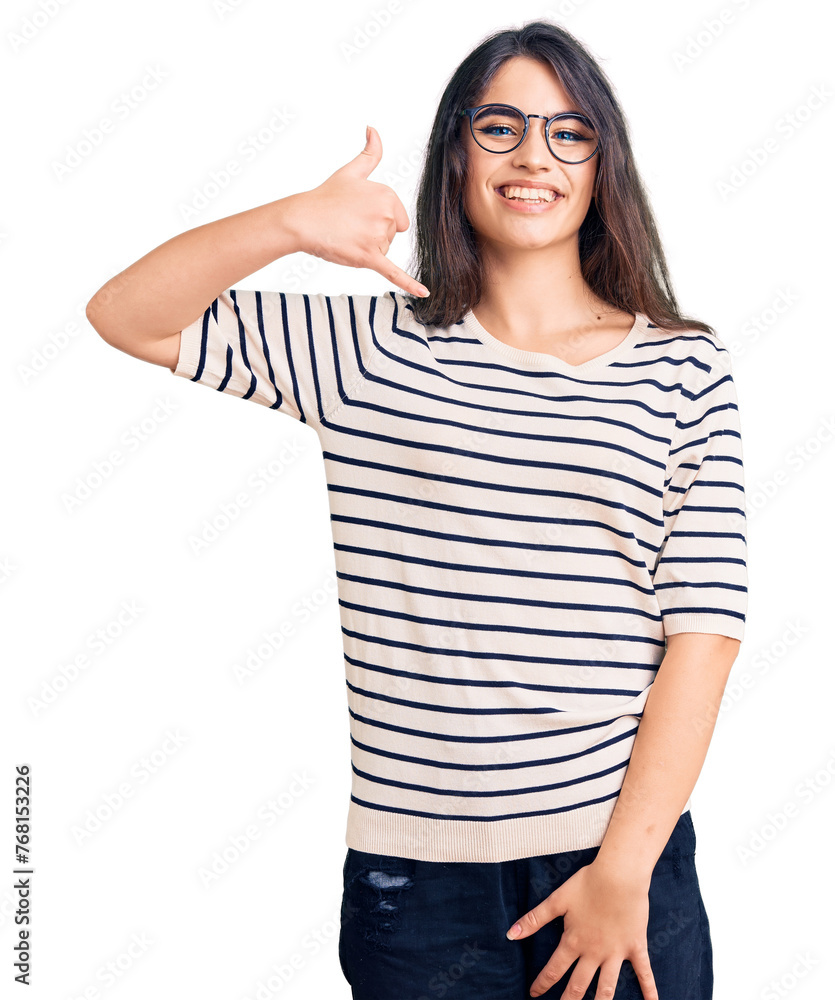 Brunette teenager girl wearing casual clothes and glasses smiling doing phone gesture with hand and fingers like talking on the telephone. communicating concepts. Brunette teenager girl wearing casual clothes and glasses smiling doing phone gesture with hand and fingers like talking on the telephone. communicating concepts.