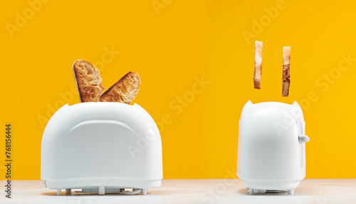 Roasted toast bread popping up of toaster with yellow wall
