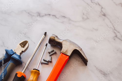 Destornillador, martillo, clavos, tornillos sobre un fondo de marmol 