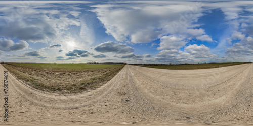 hdri 360 panorama on gravel road among fields in spring evening with awesome clouds in equirectangular full seamless spherical projection, for VR AR virtual reality content or sky replacement