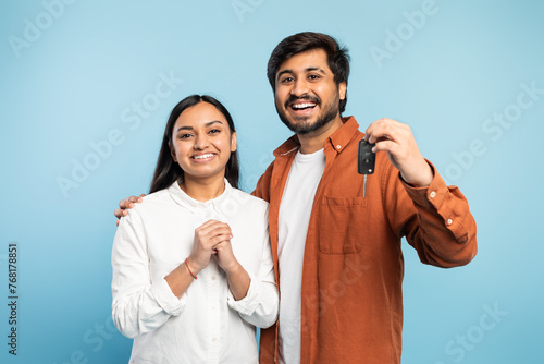 Excited young Indian couple holding up new car key, studio