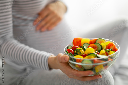 Pregnant woman holding bowl of fresh salad