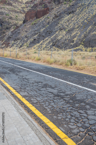 old cracked road with mountain and yellow line