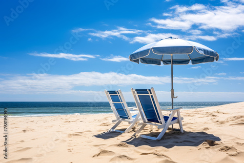 Two lounge chairs and a sunshade umbrella on the sandy beach  blue sky wit white clouds