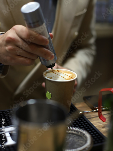 barista decorating cappuccino with cream