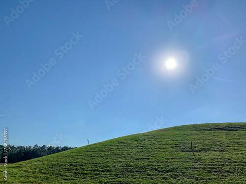 Grass covered landfill with gas vent pipes on a sunny, blue sky day