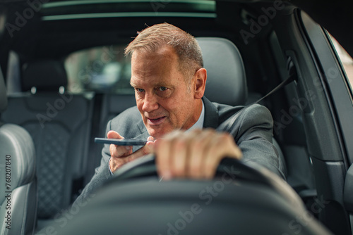 Businessman having phone call while driving to work photo