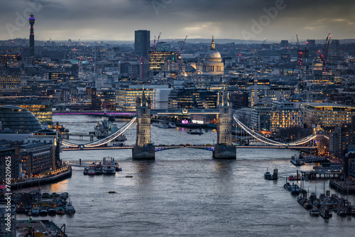 Elevated view of the illuminated Tower Bridge and St. Pauls Cathedral in London, England during a moody winter evening