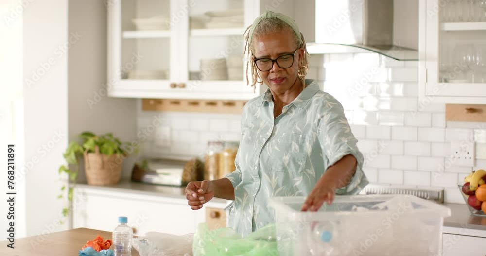 A senior African American woman sorts recycling in her kitchen A senior African American woman sorts recycling in her kitchen
